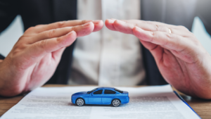 Homem cobrindo com as mãos um carro de brinquedo, para falar sobre a diferença entre seguro e proteção veicular